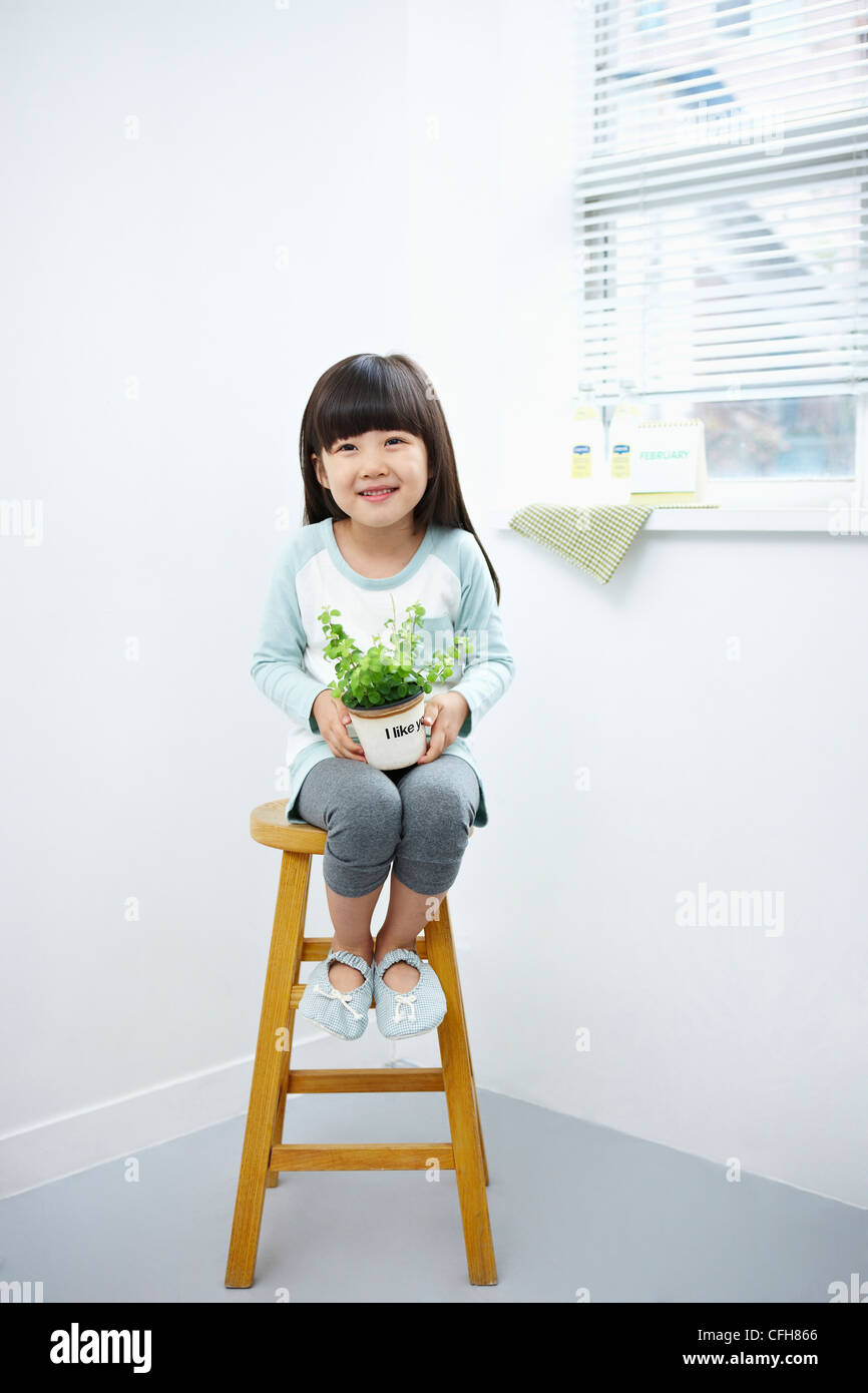 The girl holding the green plant pot on the chair Stock Photo - Alamy