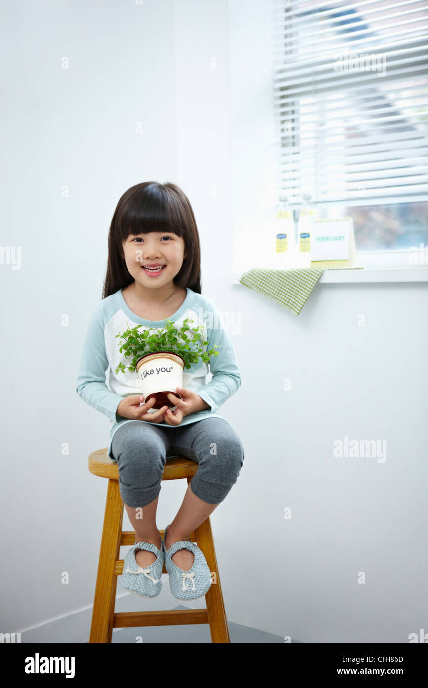 The girl holding the green plant pot on the chair Stock Photo - Alamy