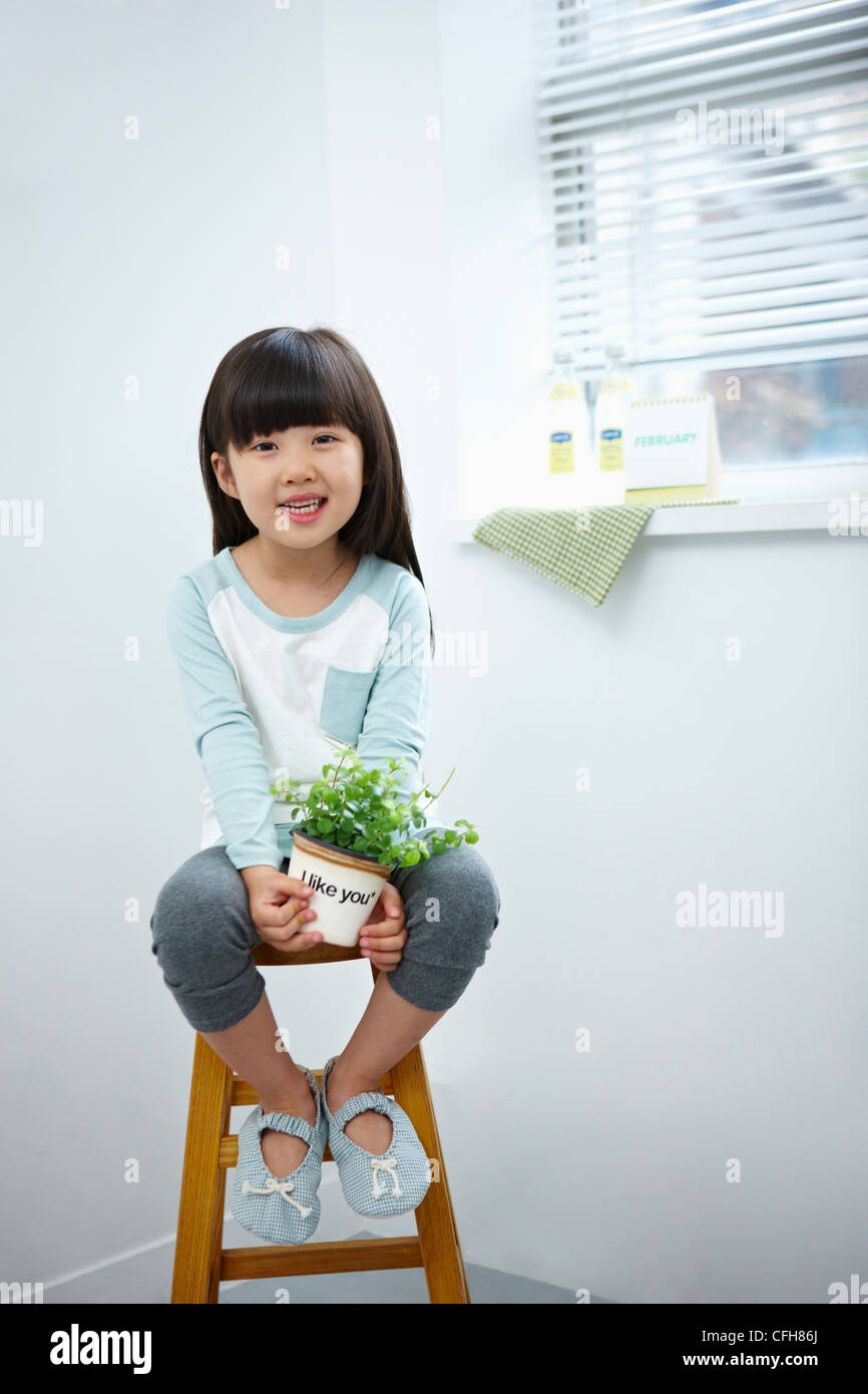 The girl holding the green plant pot on the chair Stock Photo - Alamy