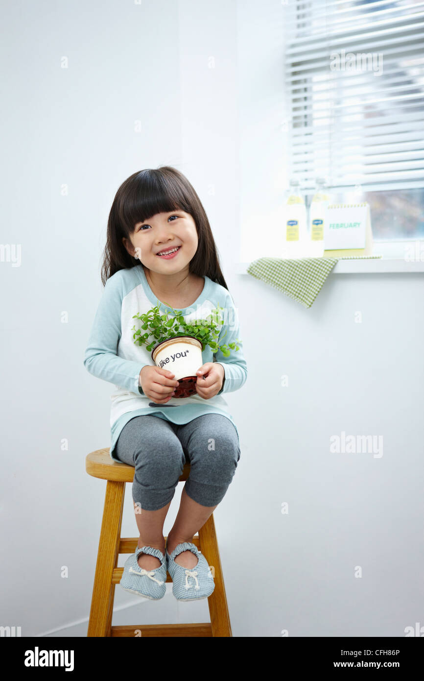 The girl holding the green plant pot on the chair Stock Photo - Alamy