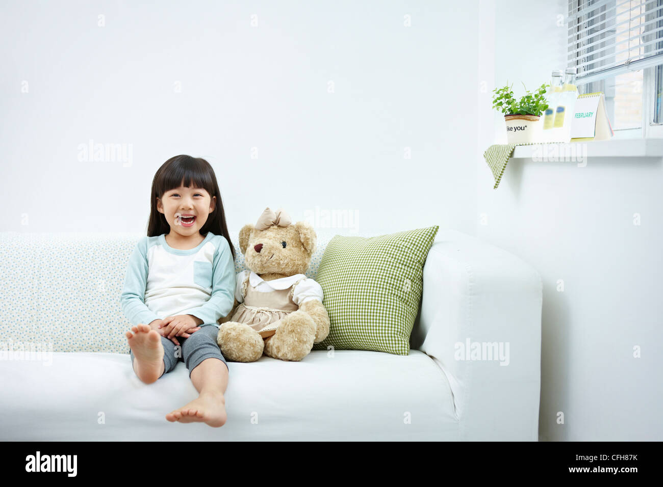 The smiling girl on the white couch Stock Photo - Alamy