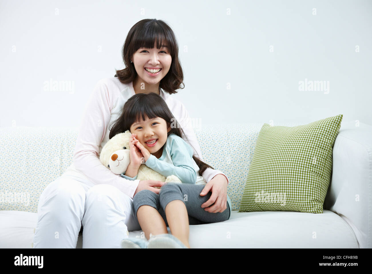The woman and girl sitting with the teddy bear Stock Photo
