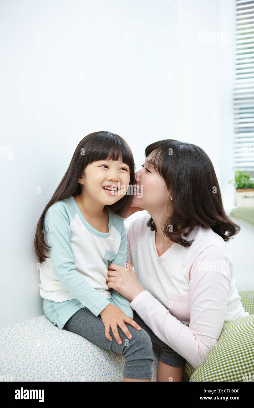 The woman whispering in girl's ear Stock Photo