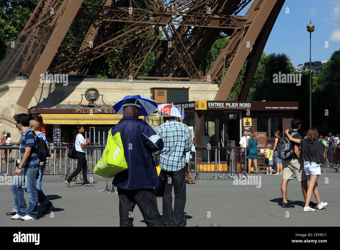 Street souvenir sellers wearing umbrellas hats at the foot of the Eiffel Tower in Paris France Stock Photo