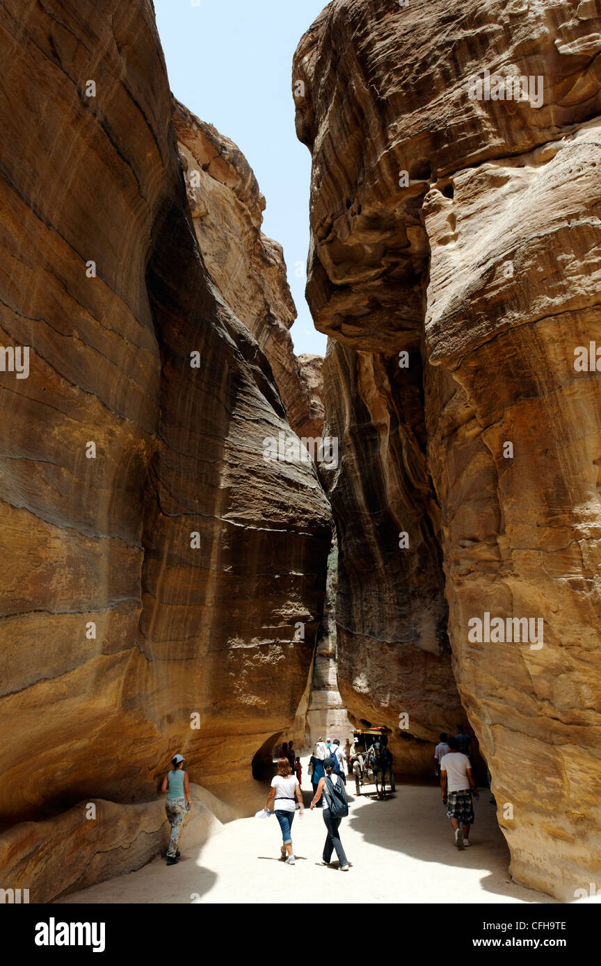 Petra. Jordan. View of tourists walking through the narrow ravine known as the Siq which gives spectacular introduction and Stock Photo