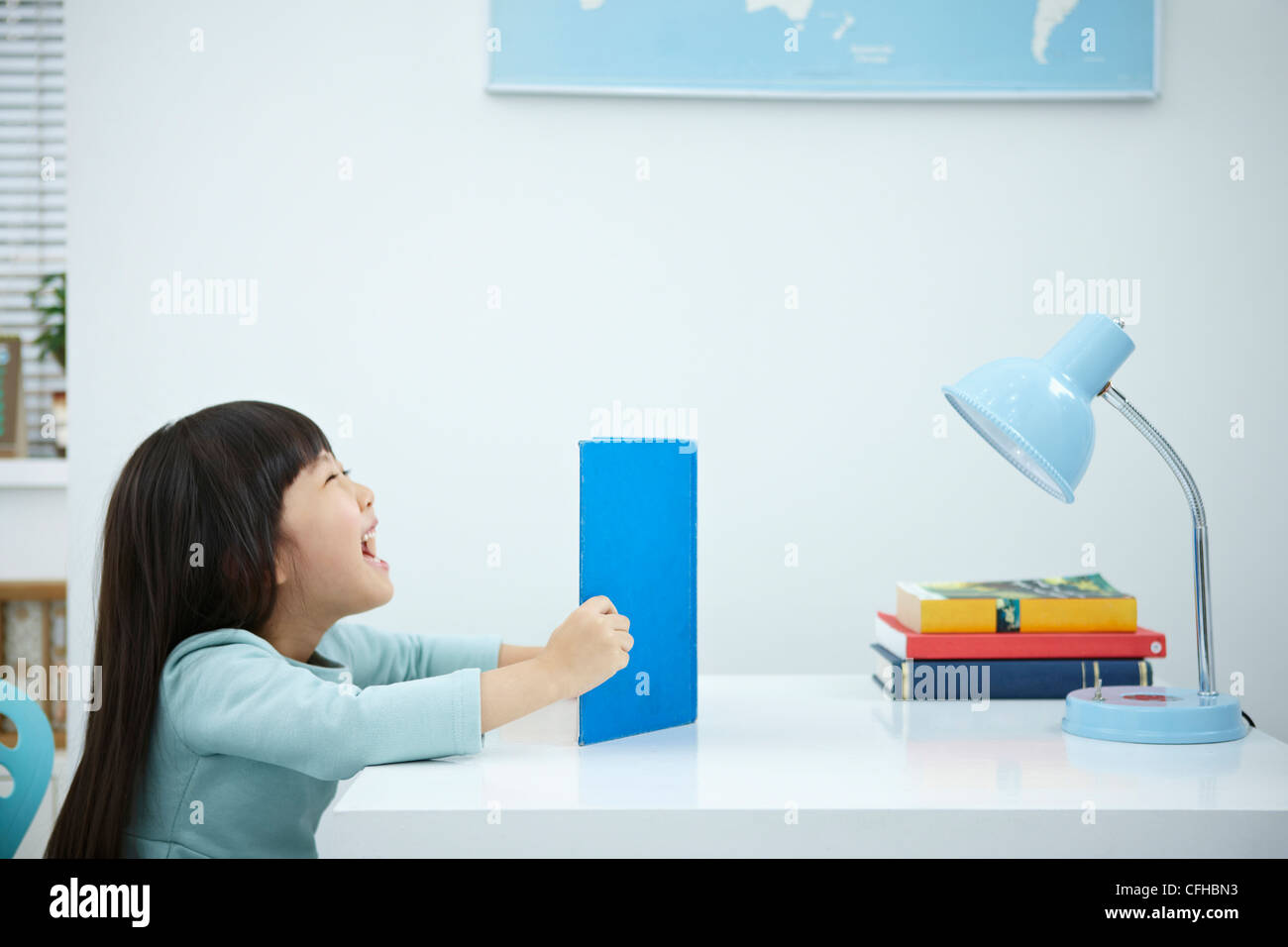 A smiling girl having a book in front of the desk Stock Photo - Alamy