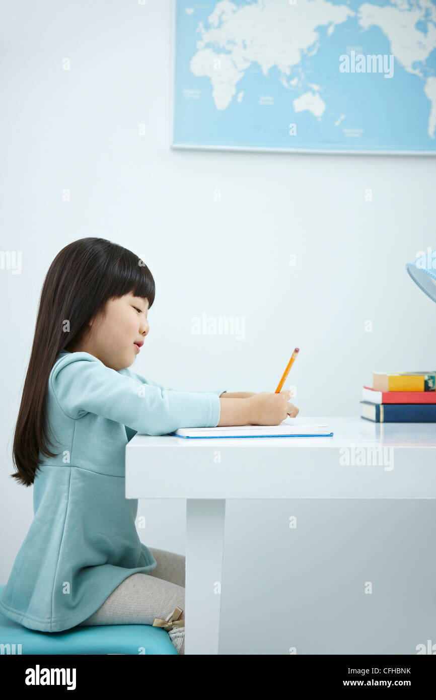 A smiling girl holding a pencil over a book Stock Photo - Alamy