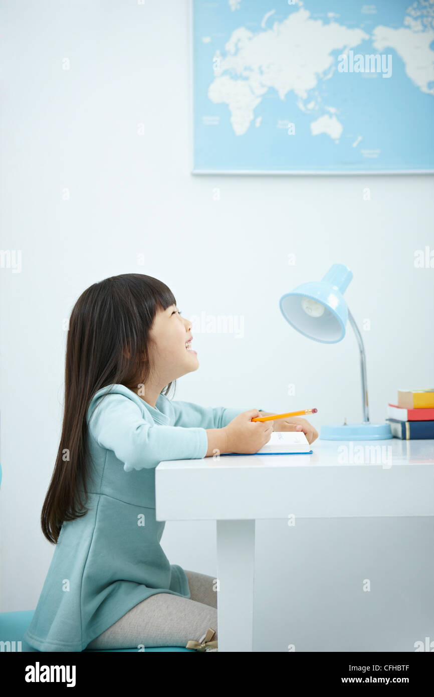 A smiling girl holding a pencil over a book Stock Photo - Alamy