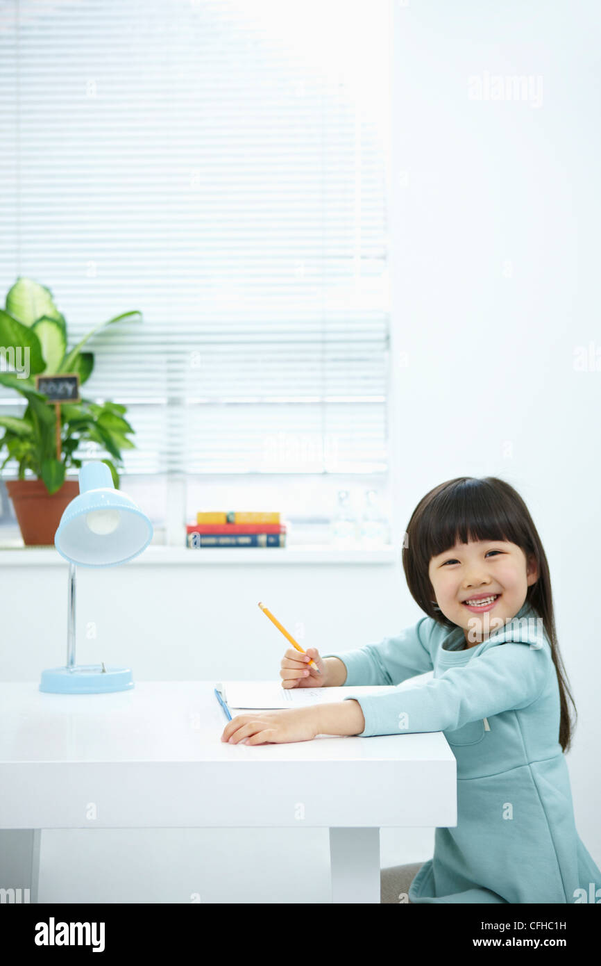 A smiling girl holding a pencil over a book Stock Photo - Alamy