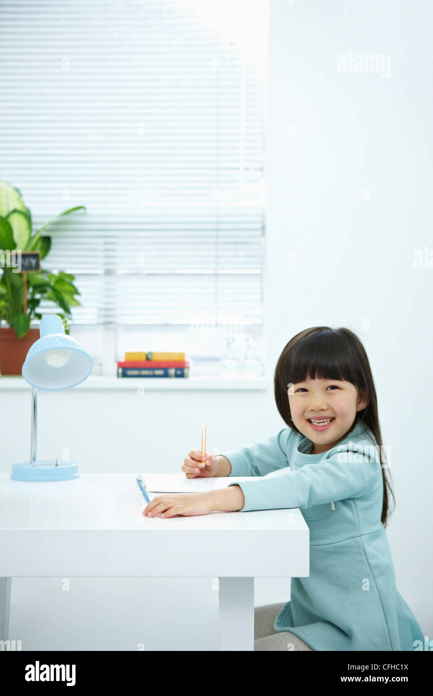 A smiling girl holding a pencil over a book Stock Photo - Alamy
