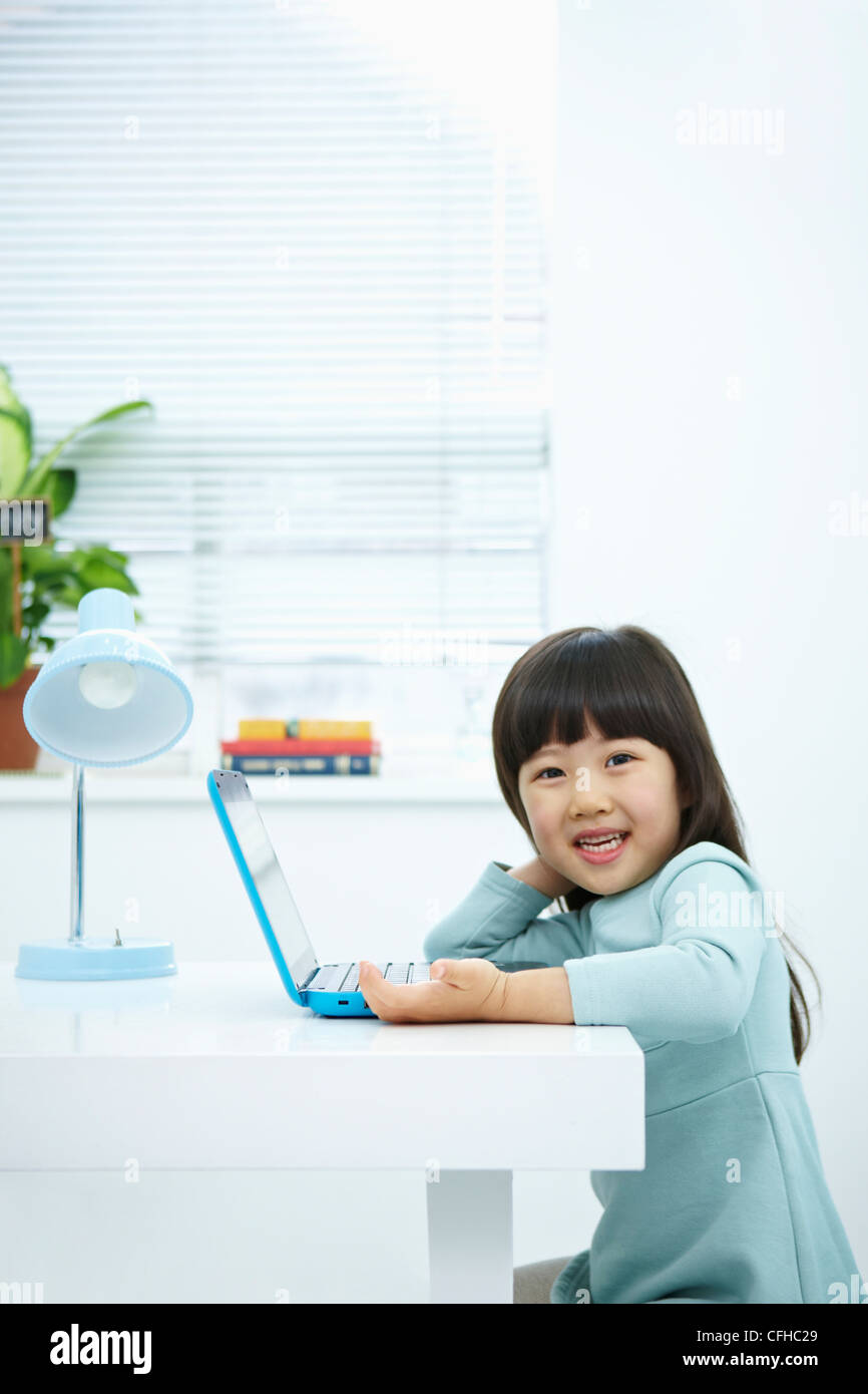 A smiling girl with a laptop on the desk Stock Photo - Alamy