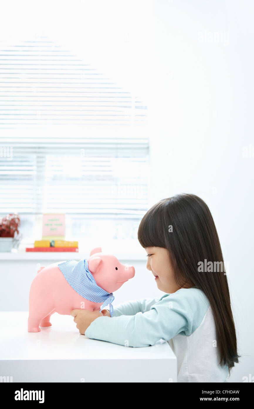 A girl facing a pink piggy bank Stock Photo - Alamy