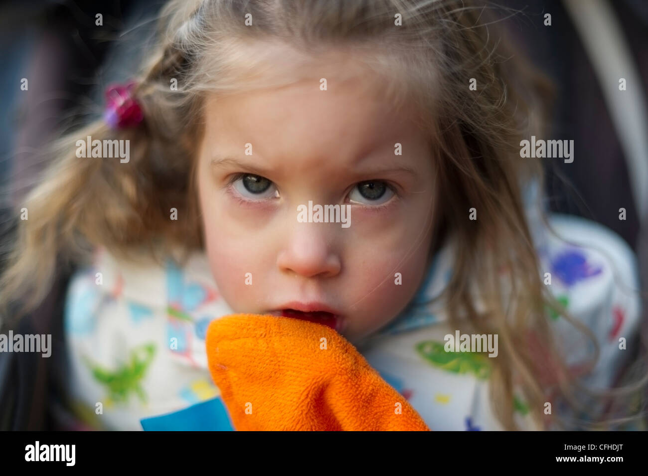 Cute girl with a blanket in her mouth frowning and sulky Stock Photo