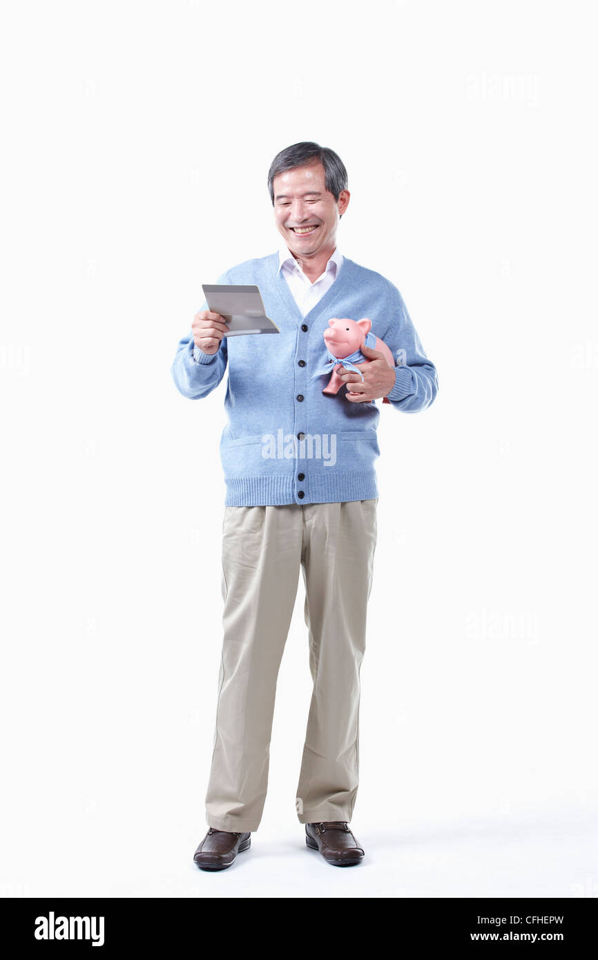 A smiling elderly man looking at the bankbook with a piggy bank Stock ...