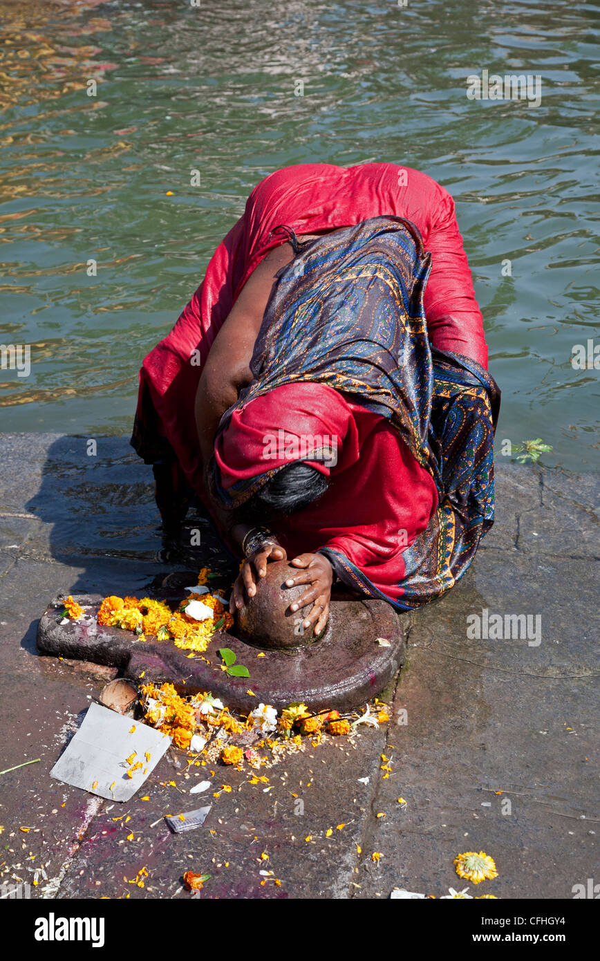 Woman prostrating in front of a Shiva lingam. Godavari river. Nasik. India Stock Photo