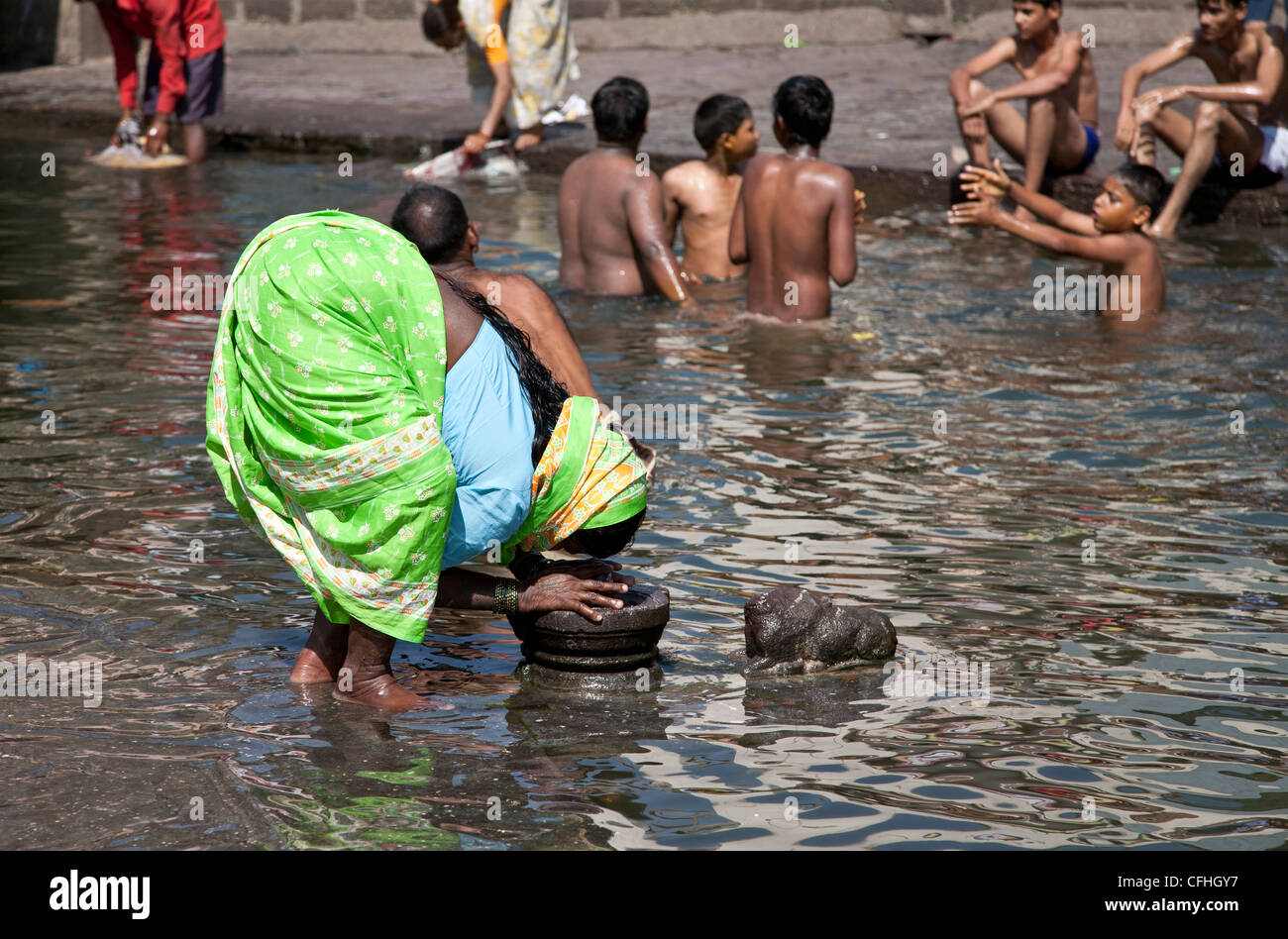 Hindu woman worshiping a Shiva lingam. Godavari river. Nasik. India Stock Photo