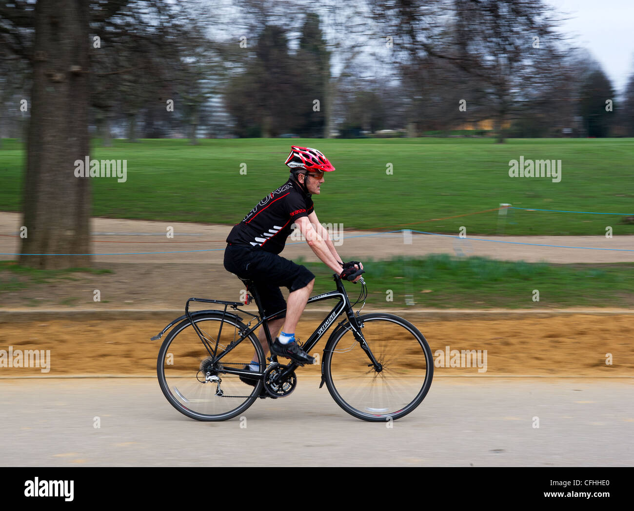 A cyclist riding through Hyde Park in London in the UK. Stock Photo