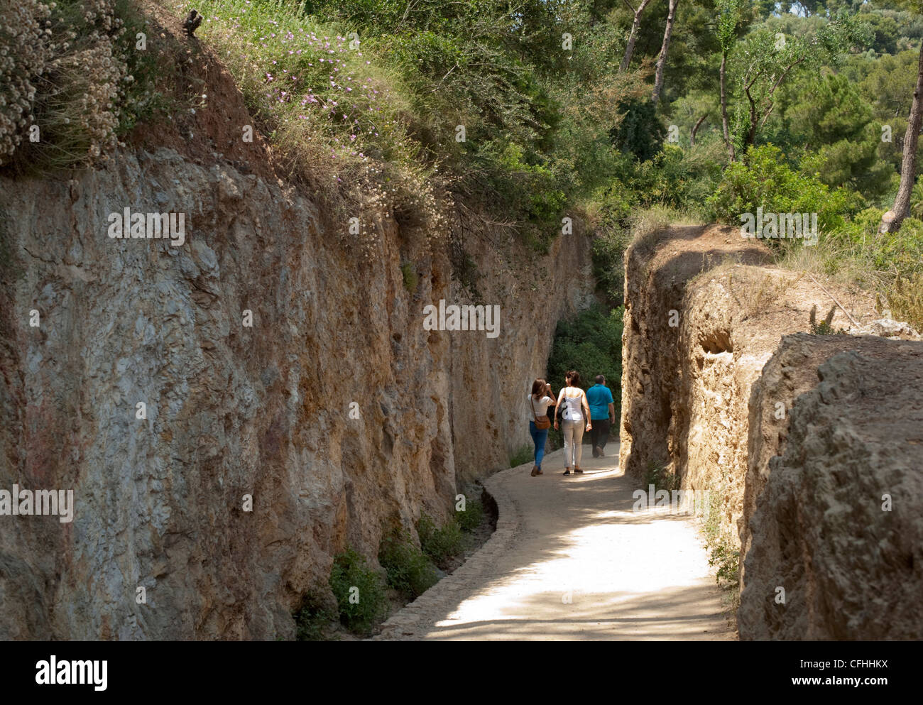 Tourists walk in the curved sculpted walkways in the gardens at Park Guell, Barcelona Stock Photo