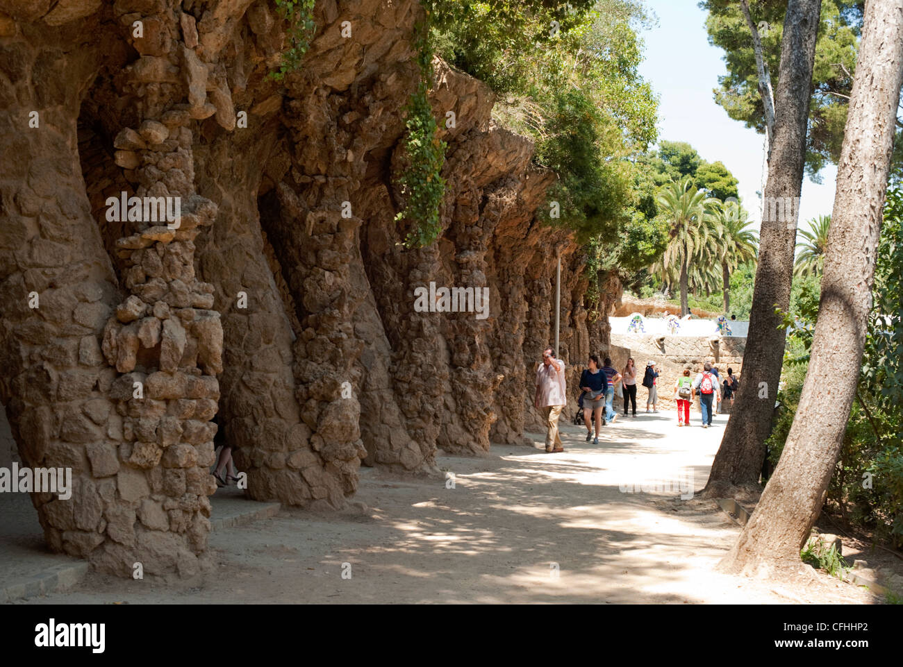 Tourists walk below the sculpted terraced walkways in Park Guell, Barcelona Stock Photo