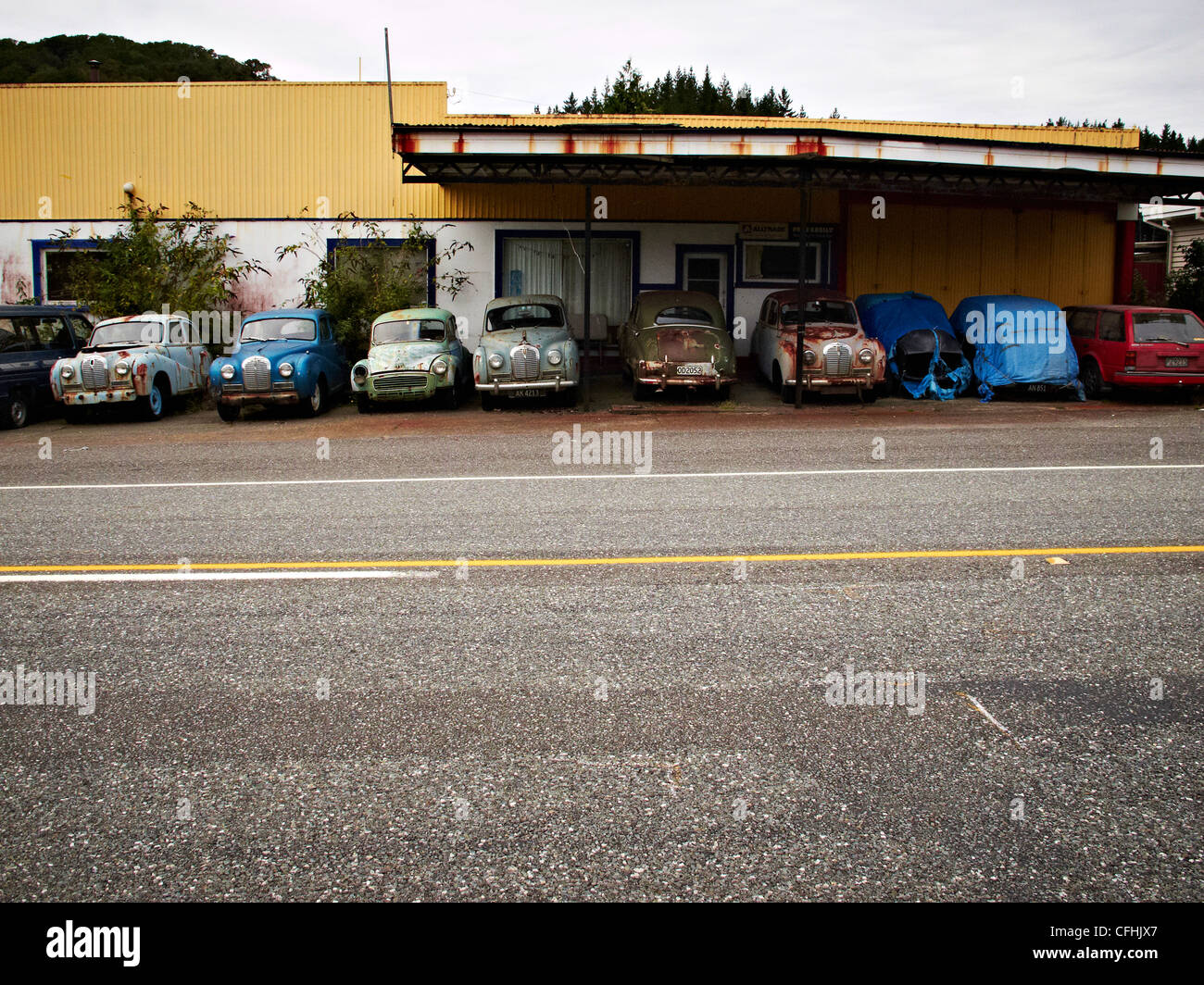 an old garage with old rusty cars by the roadside New Zealand Stock Photo