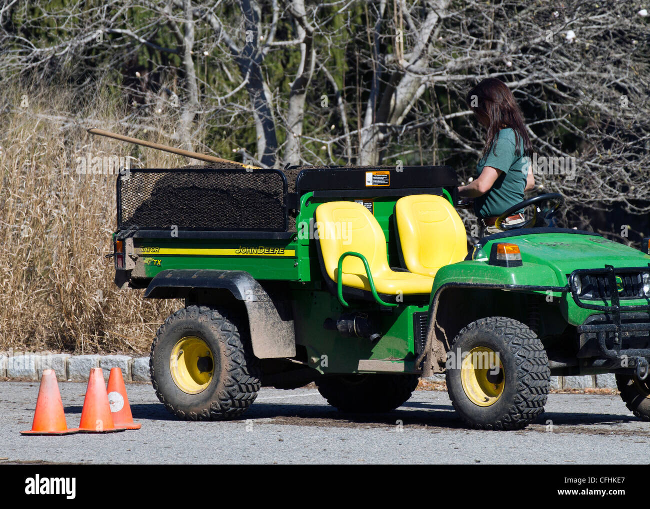 A female woman gardener with utility vehicle loaded with mulch. Stock Photo