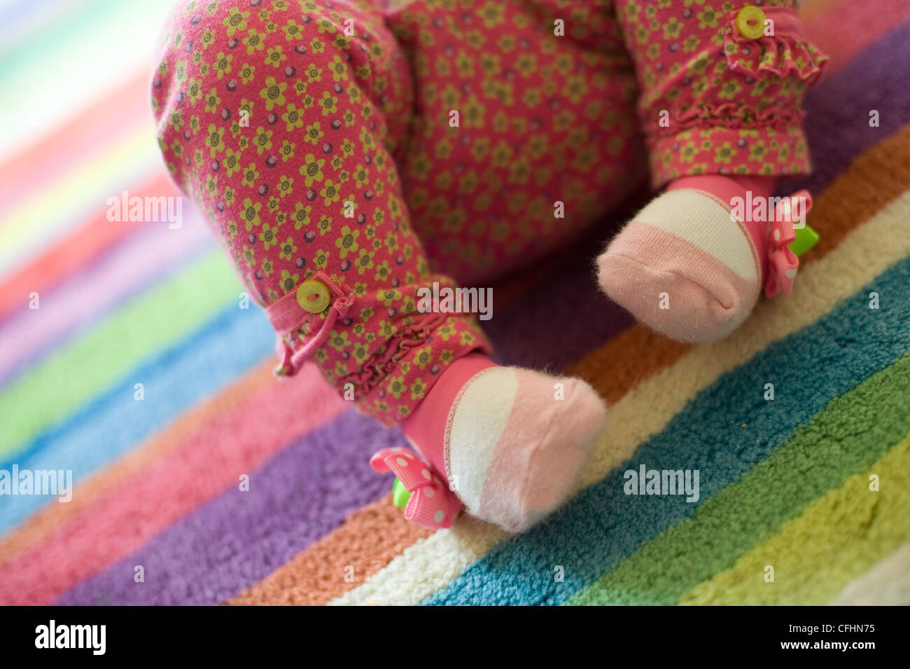 Baby girl's feet with pink flowery leggings, cute socks Stock Photo