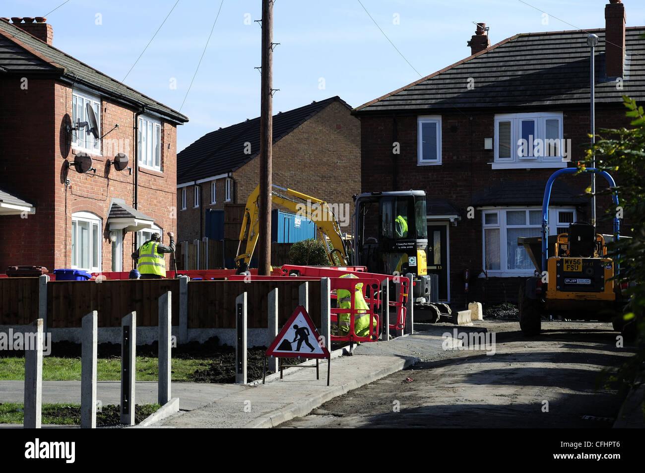 Yellow plant machinery working on front garden of domestic residence Stock Photo