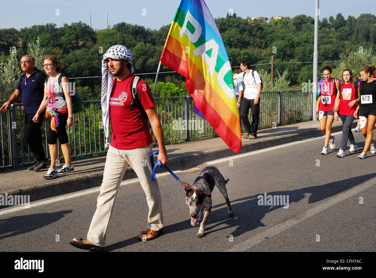 Perugia - Assisi September, 25th, 2011 : The March of Peace is 50 years old. 200,000 people on the march. A man with a peace flag and dog. Stock Photo