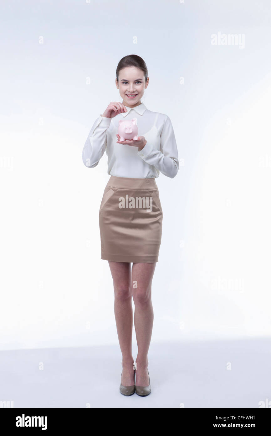 The woman putting coin into the piggy bank Stock Photo - Alamy