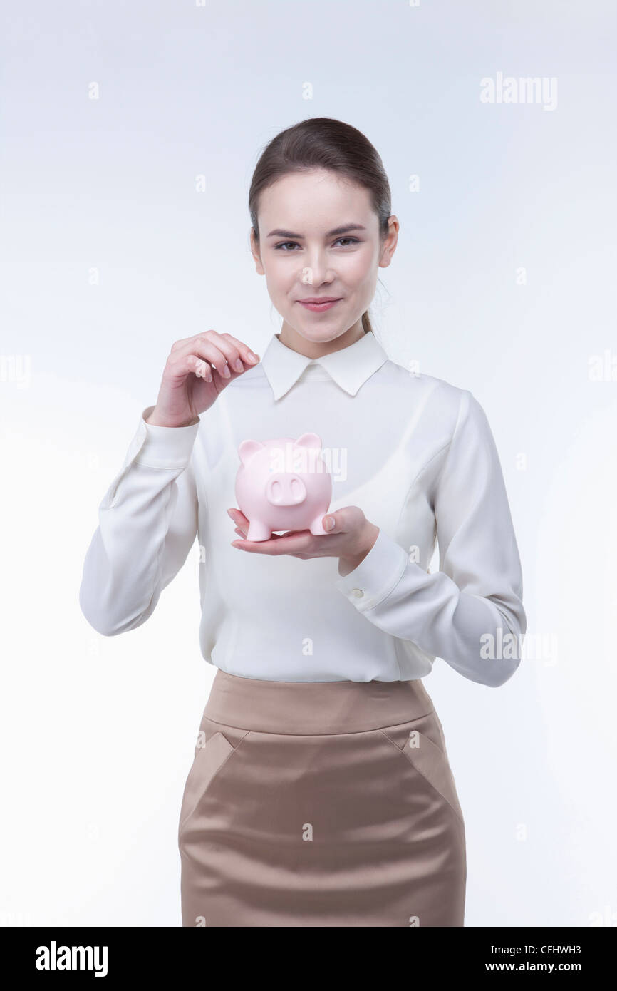 The woman putting coin into the piggy bank Stock Photo - Alamy