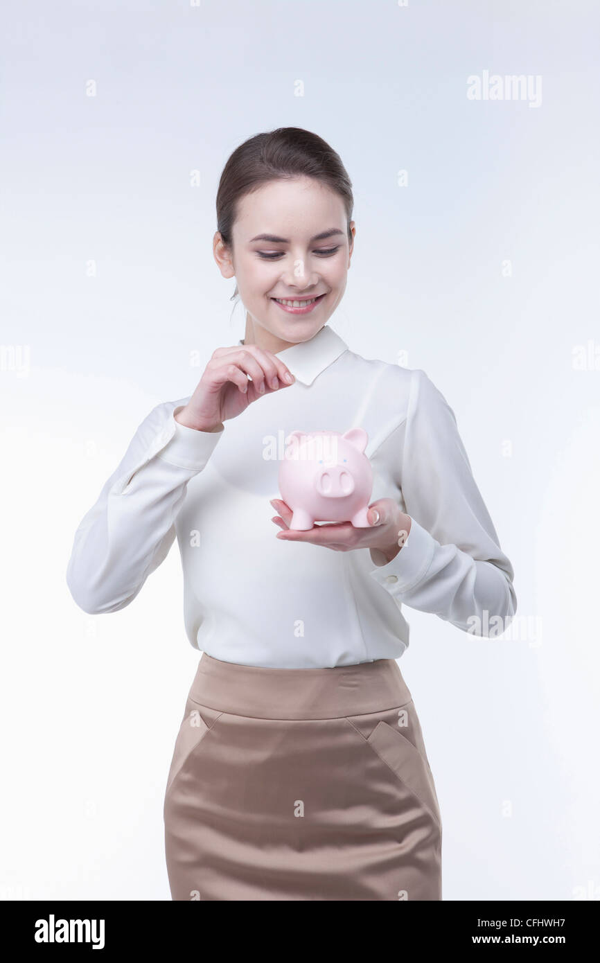 The woman putting coin into the piggy bank Stock Photo - Alamy