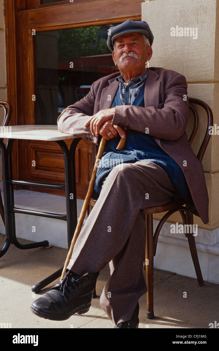 Old Greek Man sitting in front of Cafe Stock Photo