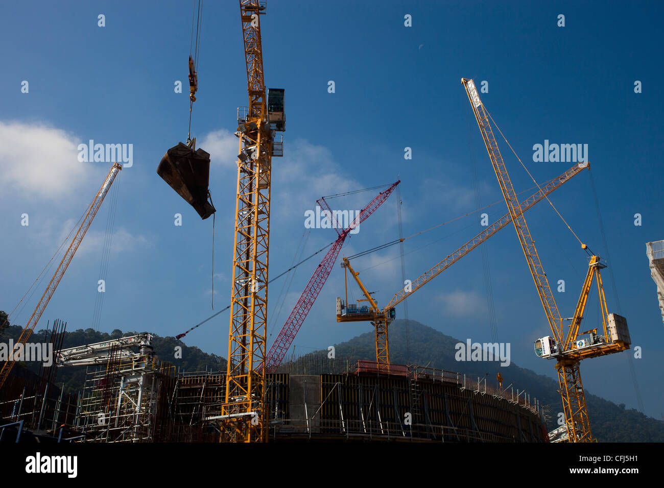 Cranes in operation at the construction of Angra 3 Nuclear Plant, Angra dos Reis, Brazil. Crane lifting a load of cement Stock Photo