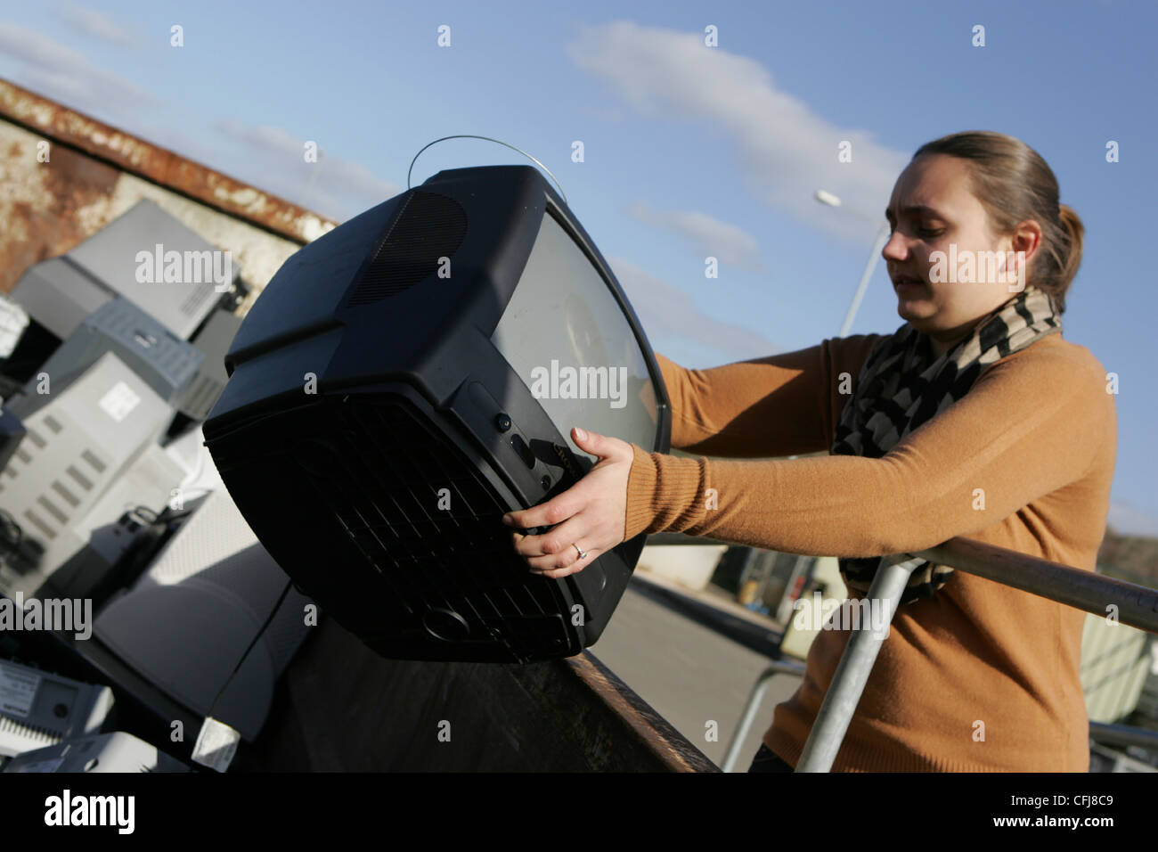 woman throws a crt tv into skip at landfill site Stock Photo