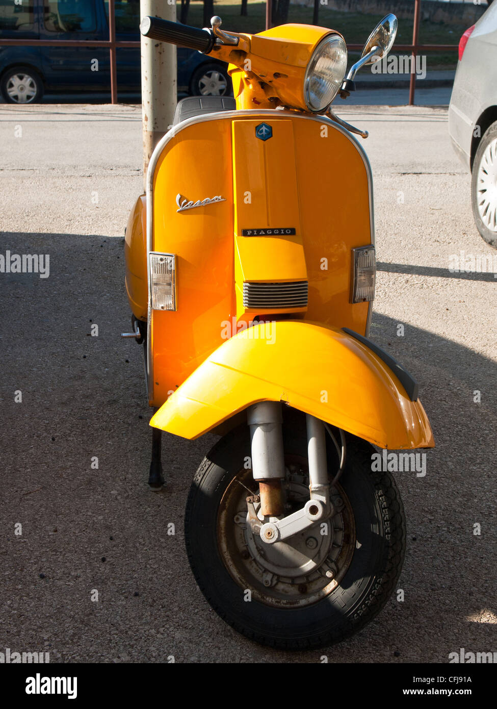 yellow vespa parked on the street Stock Photo