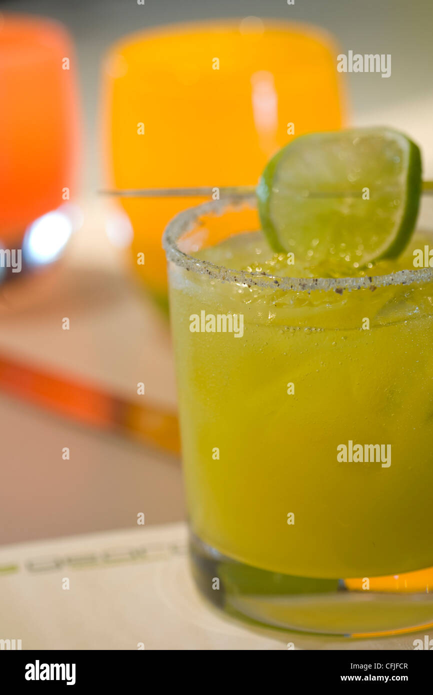 Cocktail made with babaco and and mezcal served in a Tom Collins glass with  a salty rim, and a skewered slice of fresh lime Stock Photo - Alamy