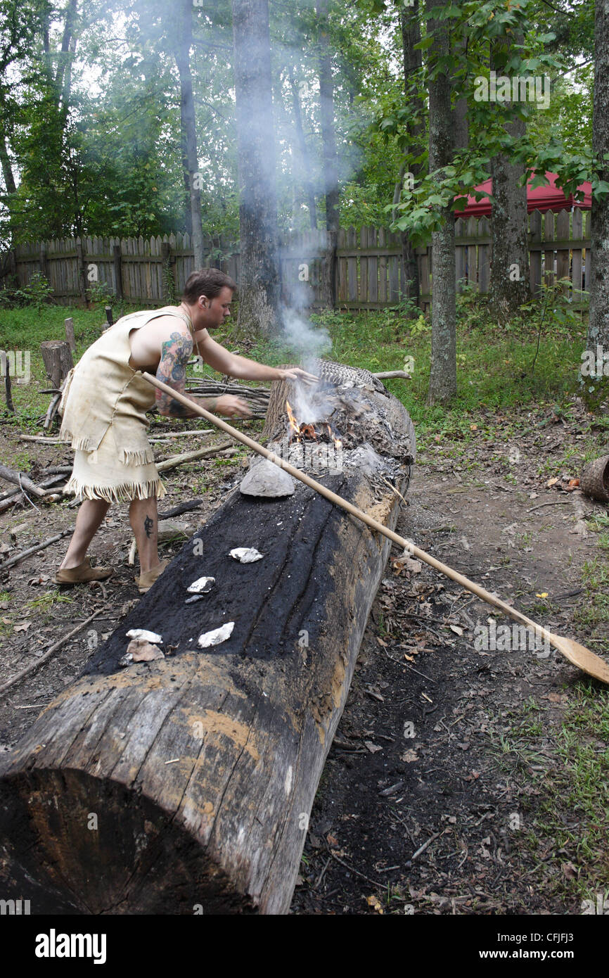Historical interpreter at Henricus,Virginia shows how native americans made dugout canoes by burning and carving from a tree. Stock Photo
