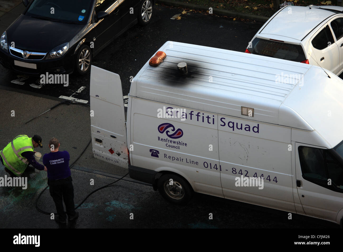 Men from the Graffiti squad  from Renfrewshire Council in Paisley, Scotland trying to remove spilled paint from the road Stock Photo