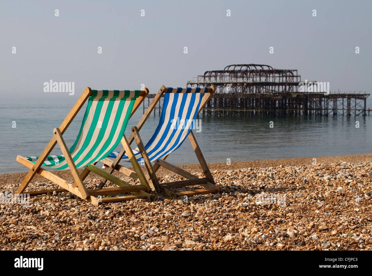 Deckchairs on Brighton beach with the burnt down pier in the background, East Sussex Stock Photo