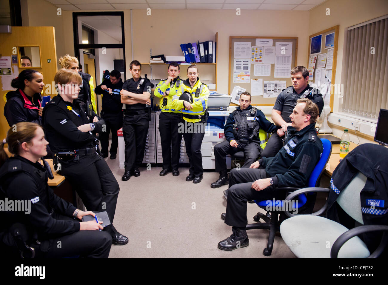 A group of uniformed police officers being briefed before deploying for duty on a saturday night, UK Stock Photo