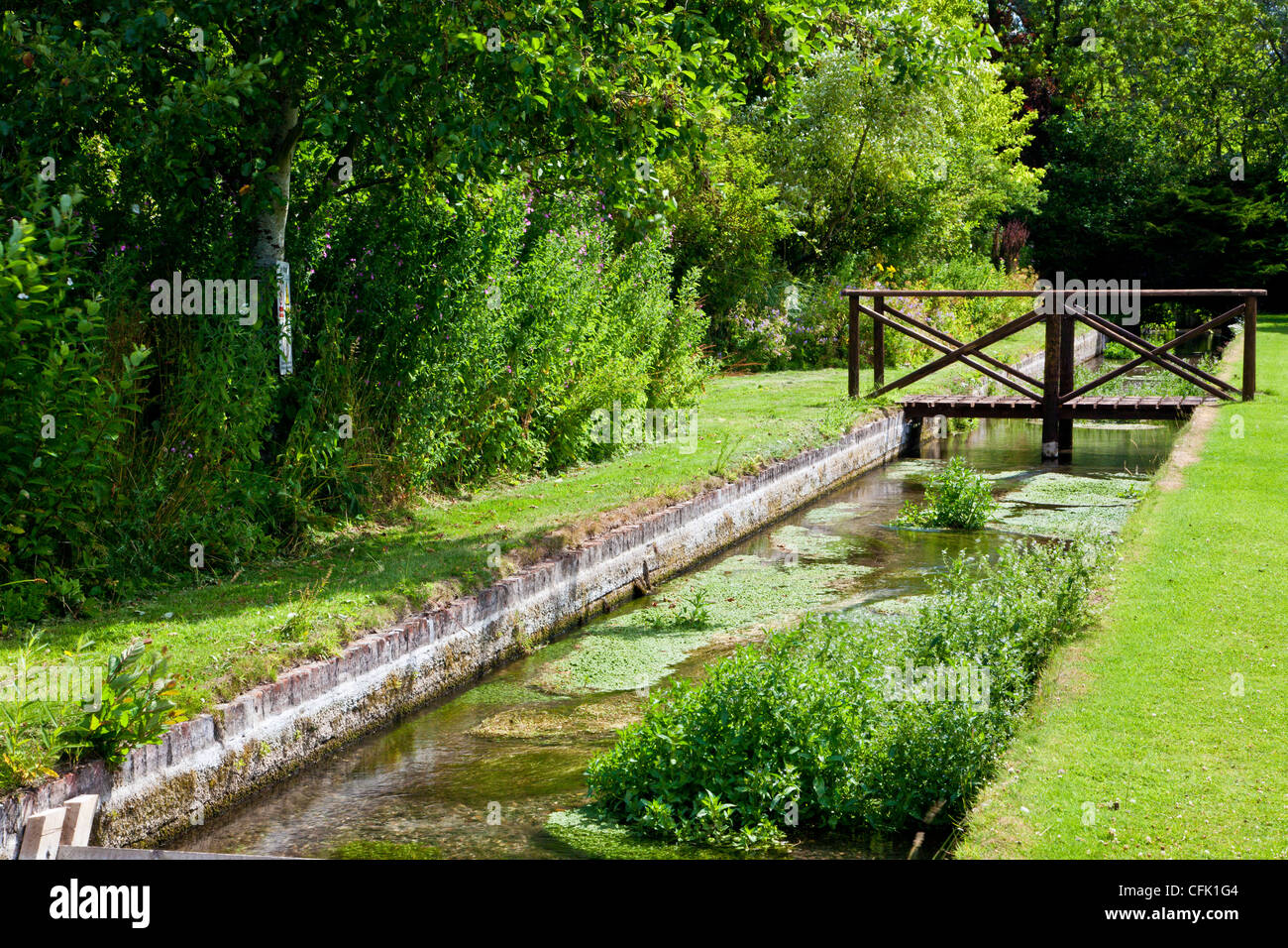 An ornamental rill and wooden footbridge in the English country garden of Littlecote Manor in Berkshire, England, UK Stock Photo