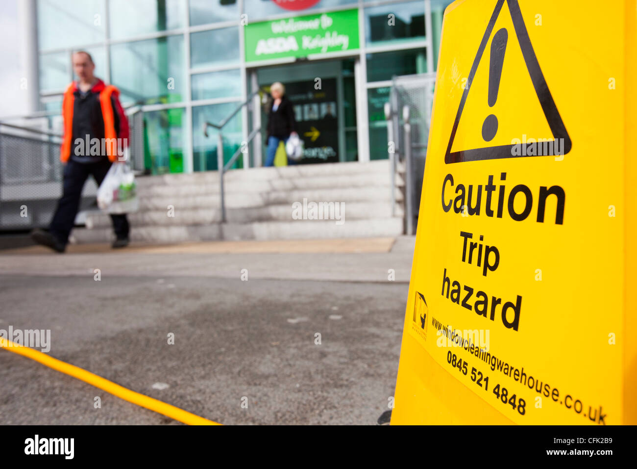 A trip hazard sign by a hose pipe outside the Keighley Asda, West Yorkshire, UK. Stock Photo