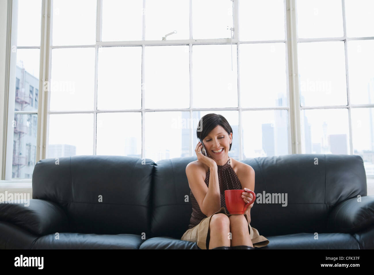 Woman on Couch holding a Mug and Talking on the Phone Stock Photo - Alamy