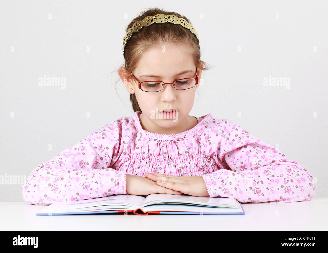 Cute schoolgirl with glasses reading book Stock Photo - Alamy