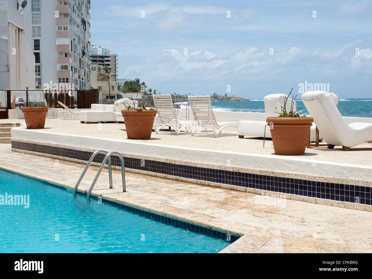 The corner of a swimming pool at the edge of the sea beside run down hotels in San Juan Puerto Rico Stock Photo
