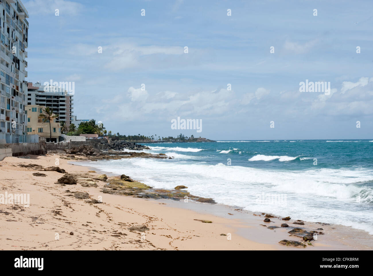 A beach beside the sea and some run down hotels and housing in San Juan, Puerto Rico Stock Photo