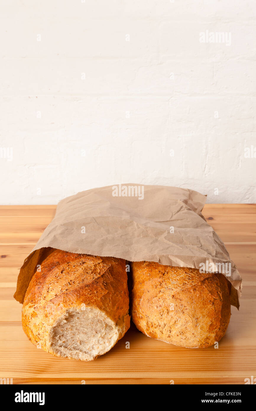 Two loaves of brown wholemeal bread wrapped in a paper bag Stock Photo