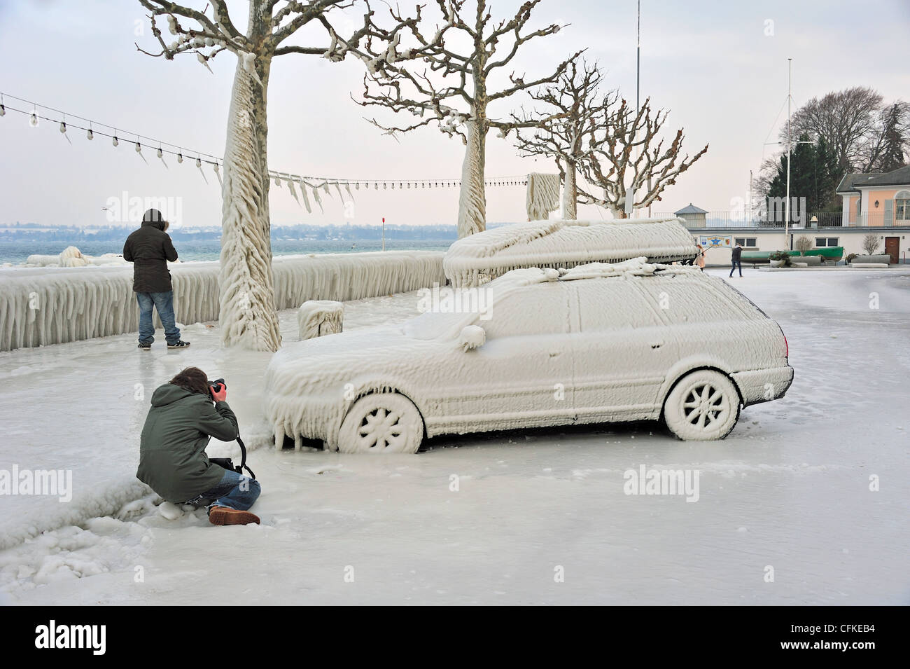 Photographer photographing a car frozen in ice in Versoix, Switzerland, by Lake Geneva Stock Photo
