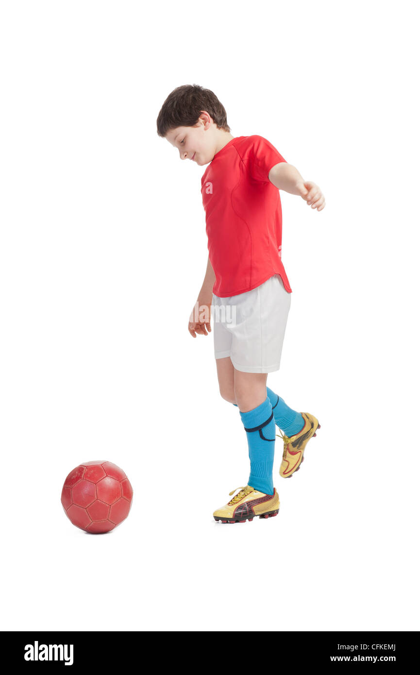 boy kickiing a red soccer ball Stock Photo
