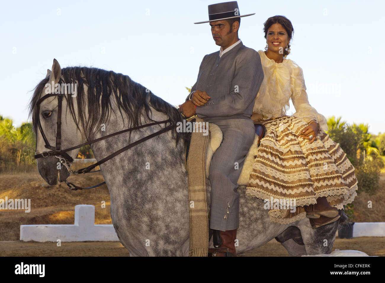 Spanish horseman with woman riding pillion on a grey Andalusian horse. Stock Photo